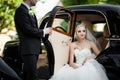 Gorgeous stylish blonde bride posing in retro black car with groom Royalty Free Stock Photo
