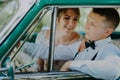 Gorgeous stylish blonde bride posing in retro green car with groom. The bride and groom are sitting inside the retro car Royalty Free Stock Photo
