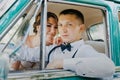 Gorgeous stylish blonde bride posing in retro green car with groom. The bride and groom are sitting inside the retro car Royalty Free Stock Photo