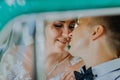 Gorgeous stylish blonde bride posing in retro green car with groom. The bride and groom are sitting inside the retro car Royalty Free Stock Photo