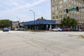 A gorgeous summer landscape along Washington Street with people walking, office buildings, bars and restaurants and cars on the