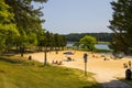 A gorgeous summer landscape at the beach with people sitting in the sand and playing in the vast blue water of Lake Acworth
