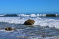 A gorgeous summer landscape at the beach with vast blue rippling ocean water with waves rolling into the silky brown sands