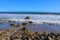 A gorgeous summer landscape at the beach with vast blue rippling ocean water with waves rolling into the silky brown sands