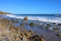 A gorgeous summer landscape at the beach with vast blue rippling ocean water with waves rolling into the silky brown sands