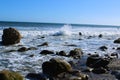 A gorgeous summer landscape at the beach with vast blue rippling ocean water with waves rolling into the silky brown sands