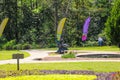 A gorgeous summer landscape in the garden with lush green trees, grass and plants and colorful flowers with people walking