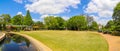 A gorgeous summer landscape in the garden with lush green trees, grass and plants, a still pond, colorful flowers with blue sky Royalty Free Stock Photo