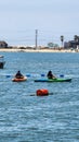 a gorgeous summer landscape at Horny Corner Beach with two women rowing colorful kayaks and people on the sandy beach