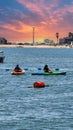 a gorgeous summer landscape at Horny Corner Beach with two women rowing colorful kayaks and people on the sandy beach