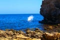 A gorgeous summer landscape at Little Corona del Mar Beach with a man jumping off a cliff into the rippling blue ocean water Royalty Free Stock Photo
