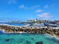 A gorgeous summer landscape at Redondo Beach Pier with a jetty made of large rocks and boats and ships sailing in the harbor Royalty Free Stock Photo