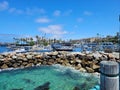 A gorgeous summer landscape at Redondo Beach Pier with a jetty made of large rocks and boats and ships sailing in the harbor Royalty Free Stock Photo