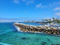 A gorgeous summer landscape at Redondo Beach Pier with a jetty made of large rocks and boats and ships sailing in the harbor Royalty Free Stock Photo