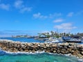 A gorgeous summer landscape at Redondo Beach Pier with a jetty made of large rocks and boats and ships sailing in the harbor Royalty Free Stock Photo