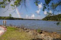 A gorgeous summer landscape with a rippling  blue lake surrounded by lush green trees, grass and plants with blue sky, clouds Royalty Free Stock Photo