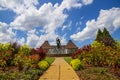 A gorgeous summer landscape with a water fountain with statue of a woman in the center surrounded by colorful flowers Royalty Free Stock Photo