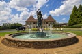 A gorgeous summer landscape with a water fountain with statue of a woman in the center surrounded by colorful flowers Royalty Free Stock Photo