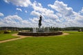 A gorgeous summer landscape with a water fountain with statue of a woman in the center surrounded by colorful flowers Royalty Free Stock Photo