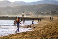 A gorgeous sunset on the beach with people walking along the beach and playing in the water with ocean waves rolling