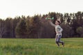 Gorgeous teenage boy running across meadow, keeping arm up and playing with toy plane, enjoying adventure in nature. Royalty Free Stock Photo