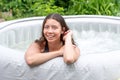 Gorgeous teenage girl with long, dark hair relaxes in the garden inflatable pool with jacuzzi