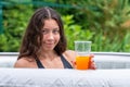 Gorgeous teenage girl with long, dark hair relaxes in the garden inflatable pool with jacuzzi