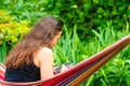 Gorgeous girl with sunglasses sitting on a hammock, relaxing and using a smartphone Royalty Free Stock Photo