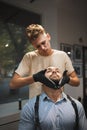 Concentrated hairdresser styling a beard. Customer and barber in a barber shop on a blurred background. Shaving concept.