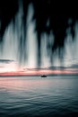 Gorgeous vertical shot of a dark blue-red sunset at sea with a boat on the horizon