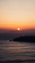 Gorgeous vertical shot of a golden sun over the horizon in Santorini, Greece at sunset