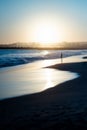 Gorgeous vertical shot of the silhouette of a person facing the low sea tide at sunrise