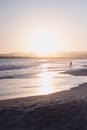 Gorgeous vertical shot of the silhouette of a woman facing the high sea tide at sunrise