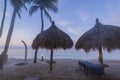 Gorgeous view early in morning on beach with umbrellas from sun on turquoise surface of water, merging with blue sky on horizon. Royalty Free Stock Photo