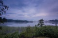 Gorgeous view of fog on the lake in the evening time on summer day. White clouds on blue sky. Europe. Sweden. Royalty Free Stock Photo