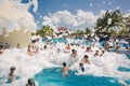 Gorgeous view of happy smiling joyful people relaxing and enjoying their time in swimming pool foam party on sunny day Royalty Free Stock Photo