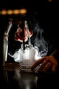 gorgeous view of illuminated steaming glass in which bartender put piece of ice using tongs Royalty Free Stock Photo