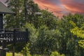 Gorgeous view of red cloudy sky during sunset and part facade of typical wooden Swedish house with wooden patio.