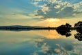 Gorgeous view of a reflective lake with a golden sun above it in Burla, Odisha India at sunset