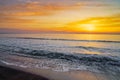 Gorgeous view of a sunset at sea with low tides at the shore under a bright orange cloudy sky