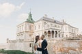 Gorgeous wedding couple embracing in sunlight near old castle in beautiful park. Stylish beautiful bride and groom gently kissing Royalty Free Stock Photo