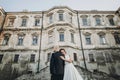 Gorgeous wedding couple embracing in sunlight near old castle in beautiful park. Stylish beautiful bride and groom gently hugging Royalty Free Stock Photo