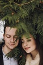 Gorgeous wedding couple embracing in winter snowy park. stylish bride in coat and  groom gently hugging under green trees in Royalty Free Stock Photo