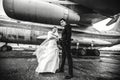 Gorgeous wedding couple poses under a huge wing of an airplane Royalty Free Stock Photo