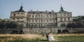 Gorgeous wedding couple walking in sunlight near old castle in beautiful park. Stylish beautiful bride and groom holding hands on Royalty Free Stock Photo