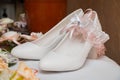 Gorgeous white bridal shoes with a peach garter. Beige flowers Royalty Free Stock Photo