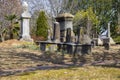 A gorgeous winter landscape in the graveyard with headstones, graves, bare winter trees, lush green trees, plants and flowers