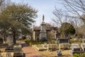 A gorgeous winter landscape in the graveyard with headstones, graves, bare winter trees, lush green trees, plants and flowers