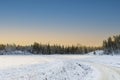 Gorgeous winter nature landscape view. Bend of country road and green forest trees on blue sky background