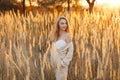 A gorgeous woman in an autumn field illuminated by the warm sun of an evening sunset. Golden ears of corn. Autumn Royalty Free Stock Photo